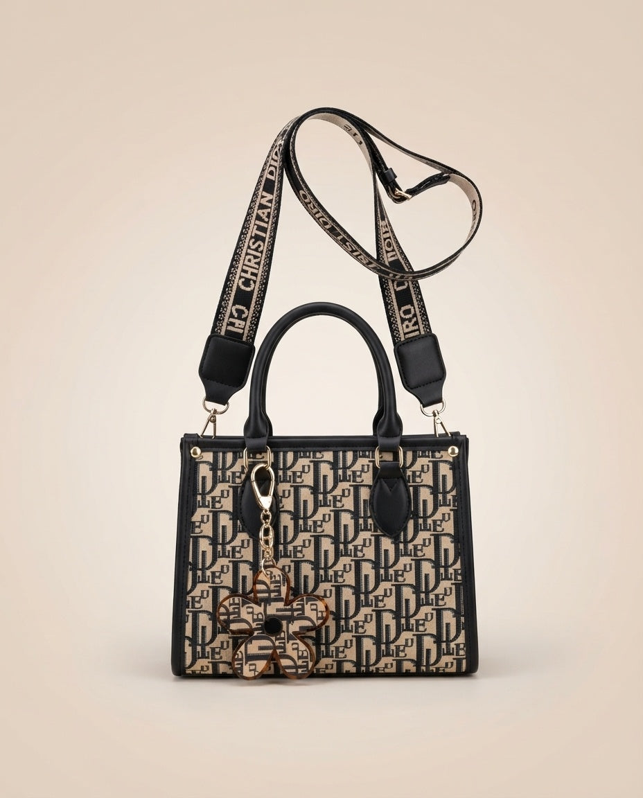 Structured tote bag with navy-and-black logo print, top handles, and flower charm